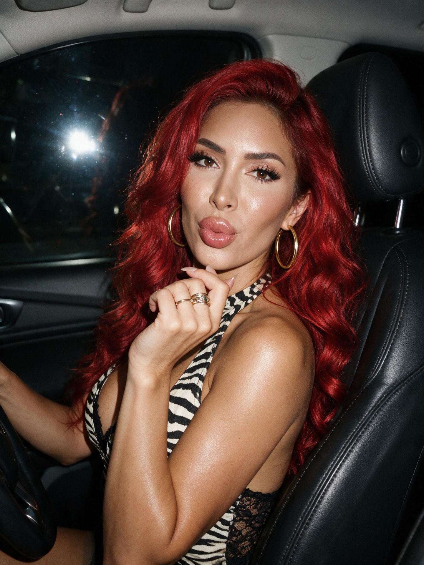 Farrah Abraham with vivid red hair posing in a car